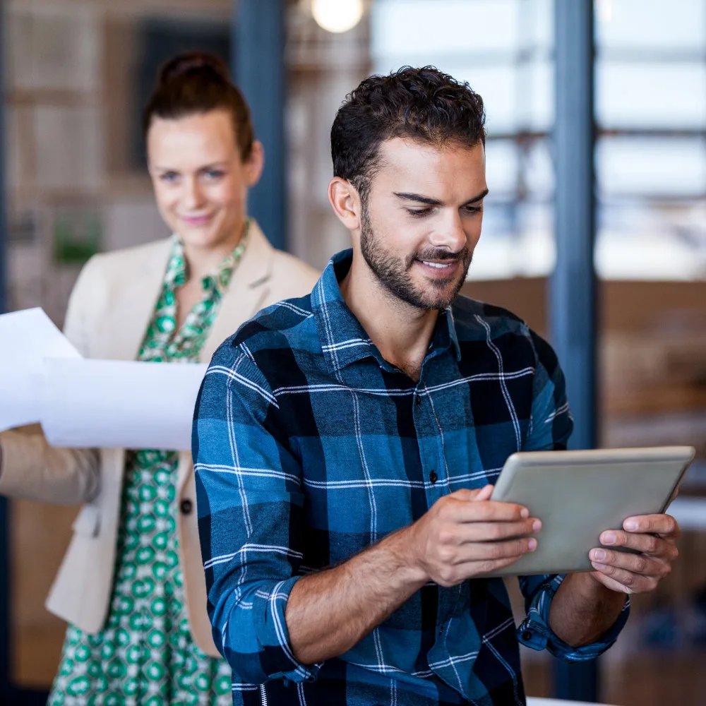joven en una tablet mientras una mujer detrás lo mira